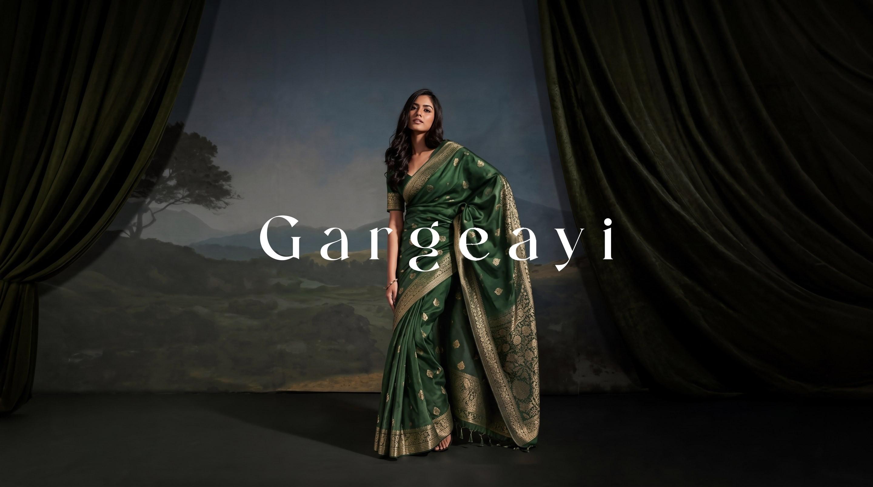 Gargeayi — emerald silk saree with woven zari border, on a painted-landscape stage